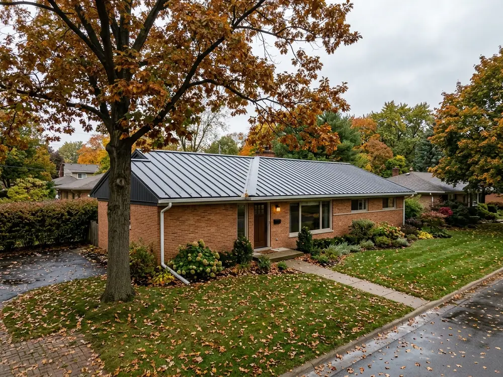Charcoal aluminum standing seam roof on a single-storey brick house, seams running to a straight ridge